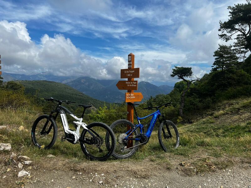 Cinq cyclistes et leurs VTT électriques au sommet, un large panorama sur l'arrière-pays
