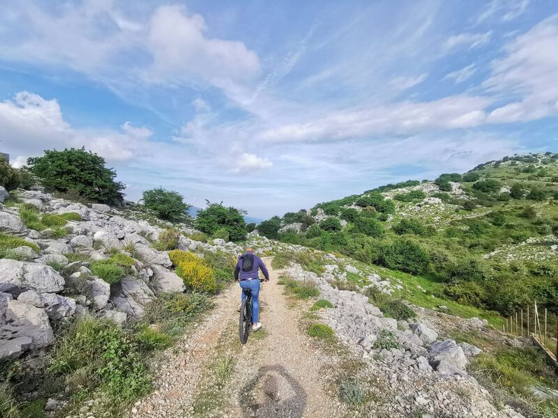 Deux VTT électriques devant un ancien fort en pierre, les nuages accrochés aux sommets